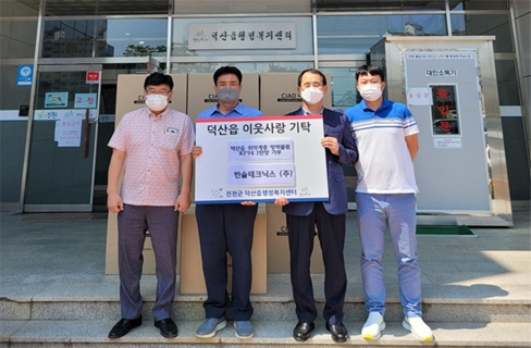 Attendees holding a mask donation sign at a community donation ceremony in Deoksan-eup